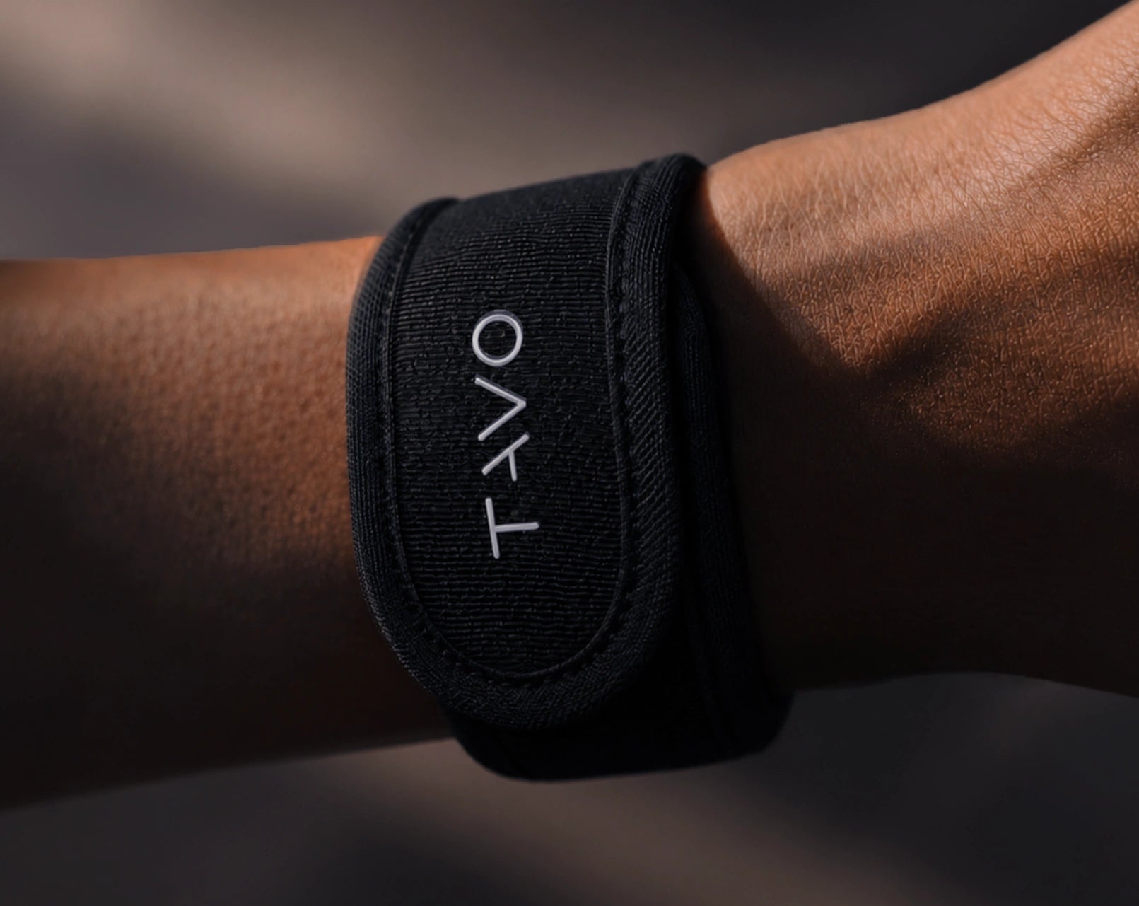 Black TAVO V2 wristband with against a dark background